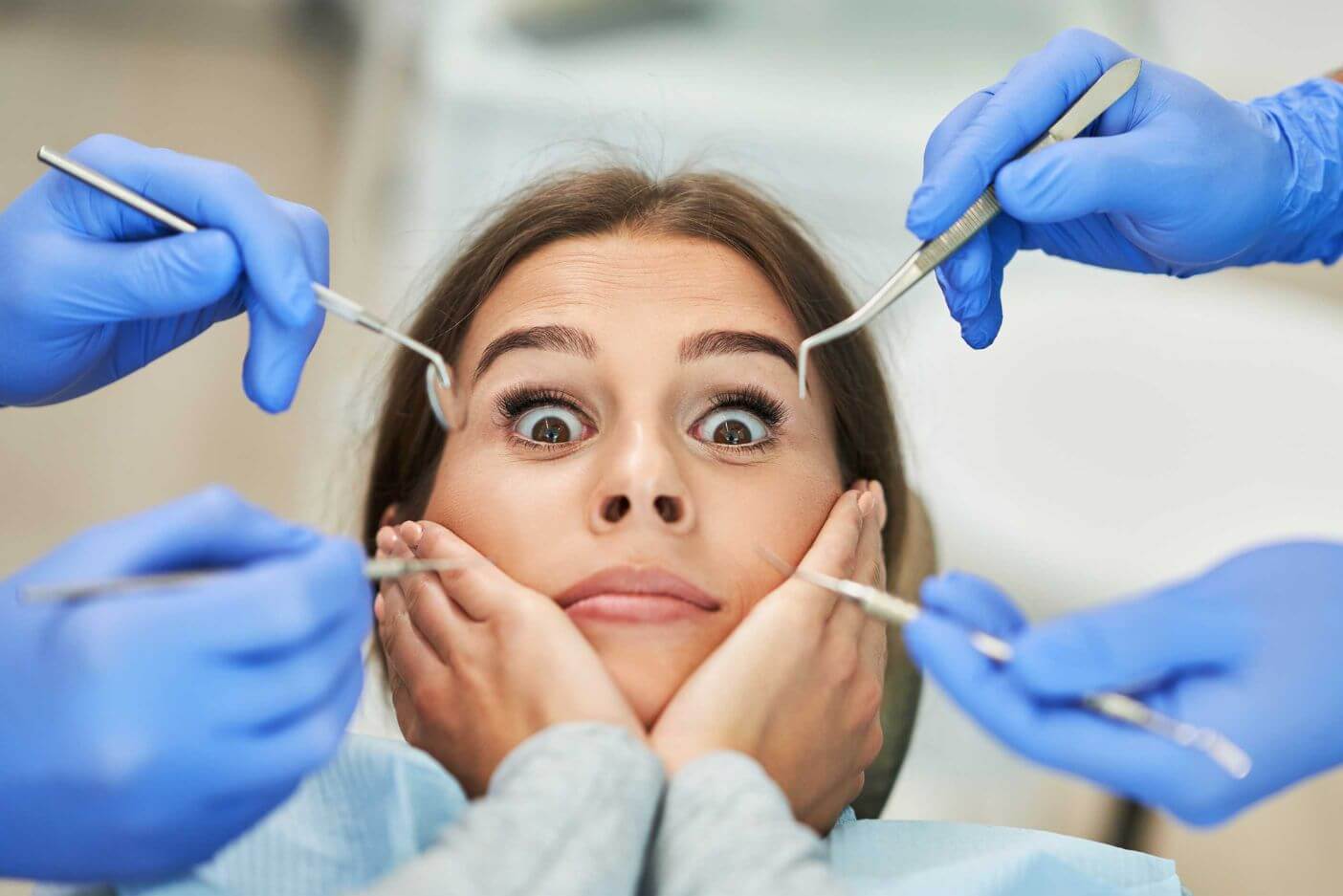 A woman with wide, frightened eyes is at the dentist.