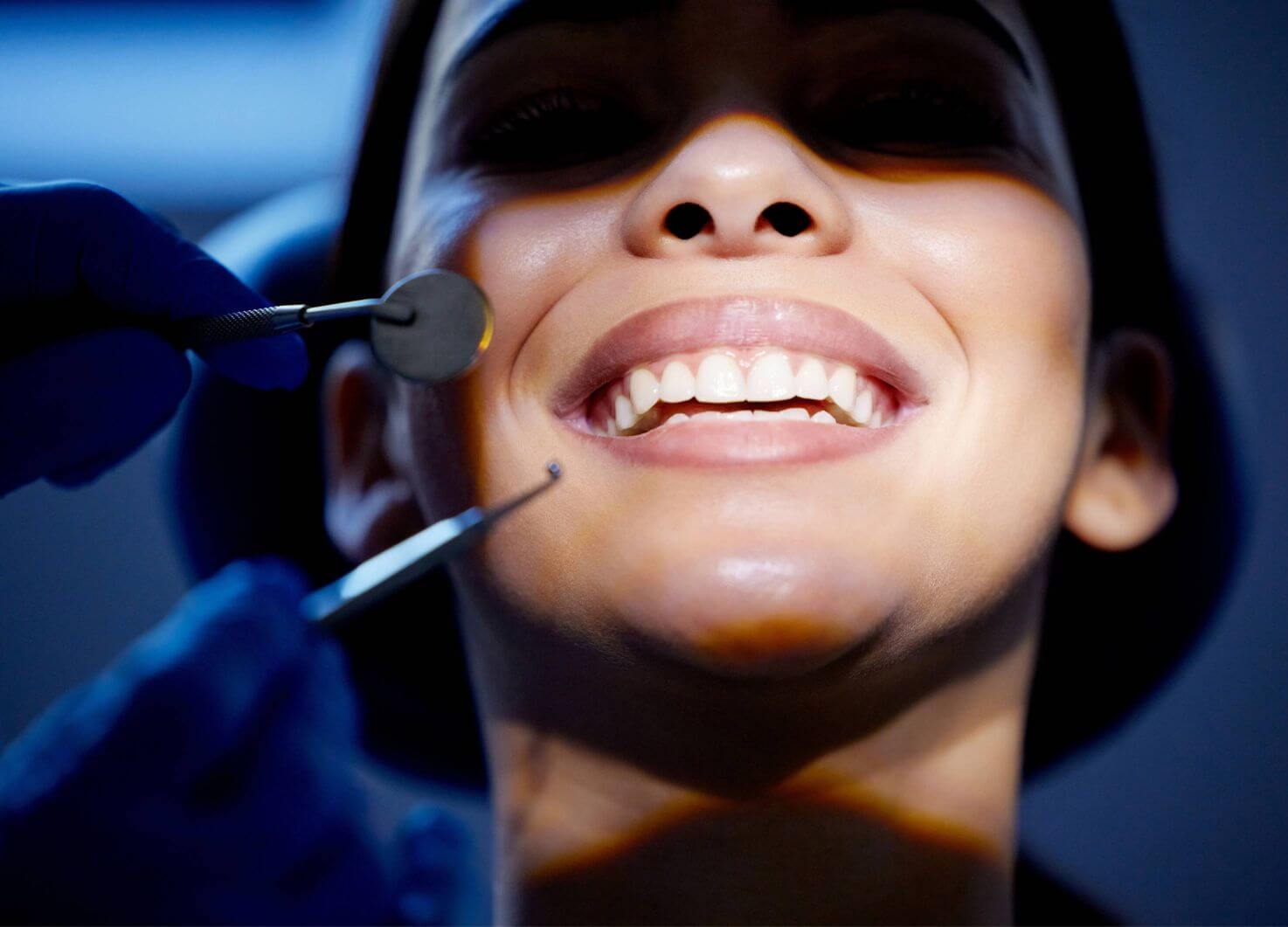 Child smiling during a dental examination while a dentist uses a mirror and dental probe